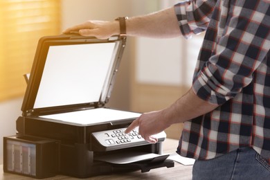 Photo of Man using modern multifunction printer in office, closeup