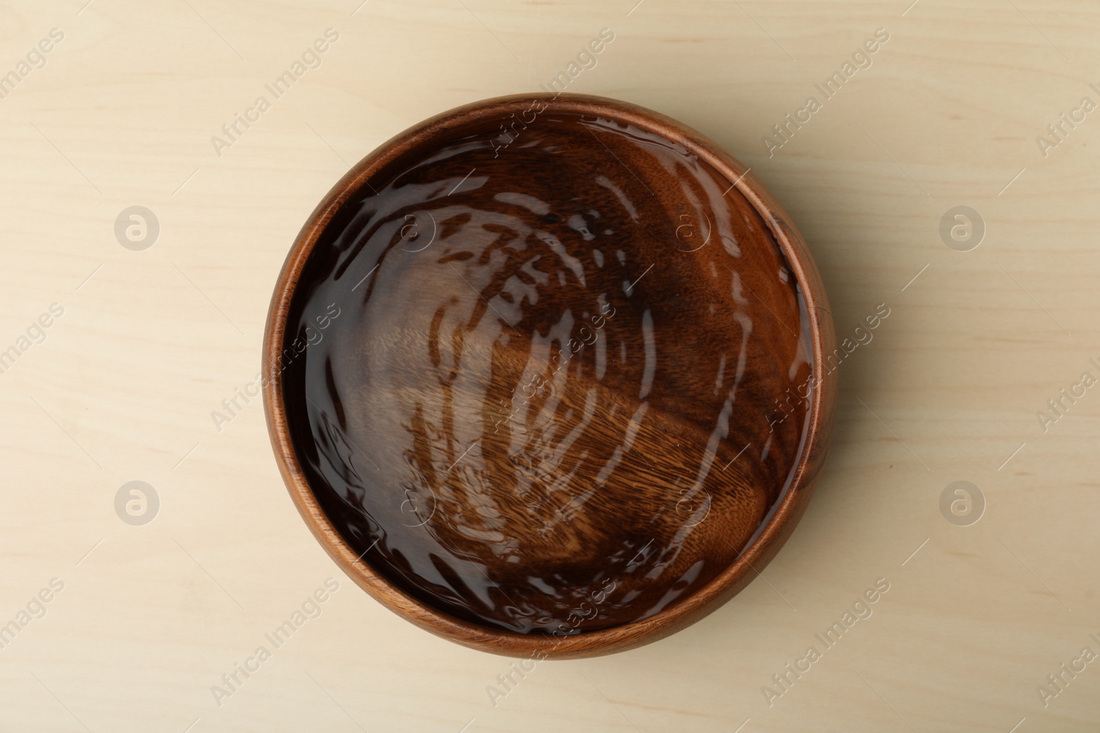 Photo of Bowl full of water on wooden table, top view