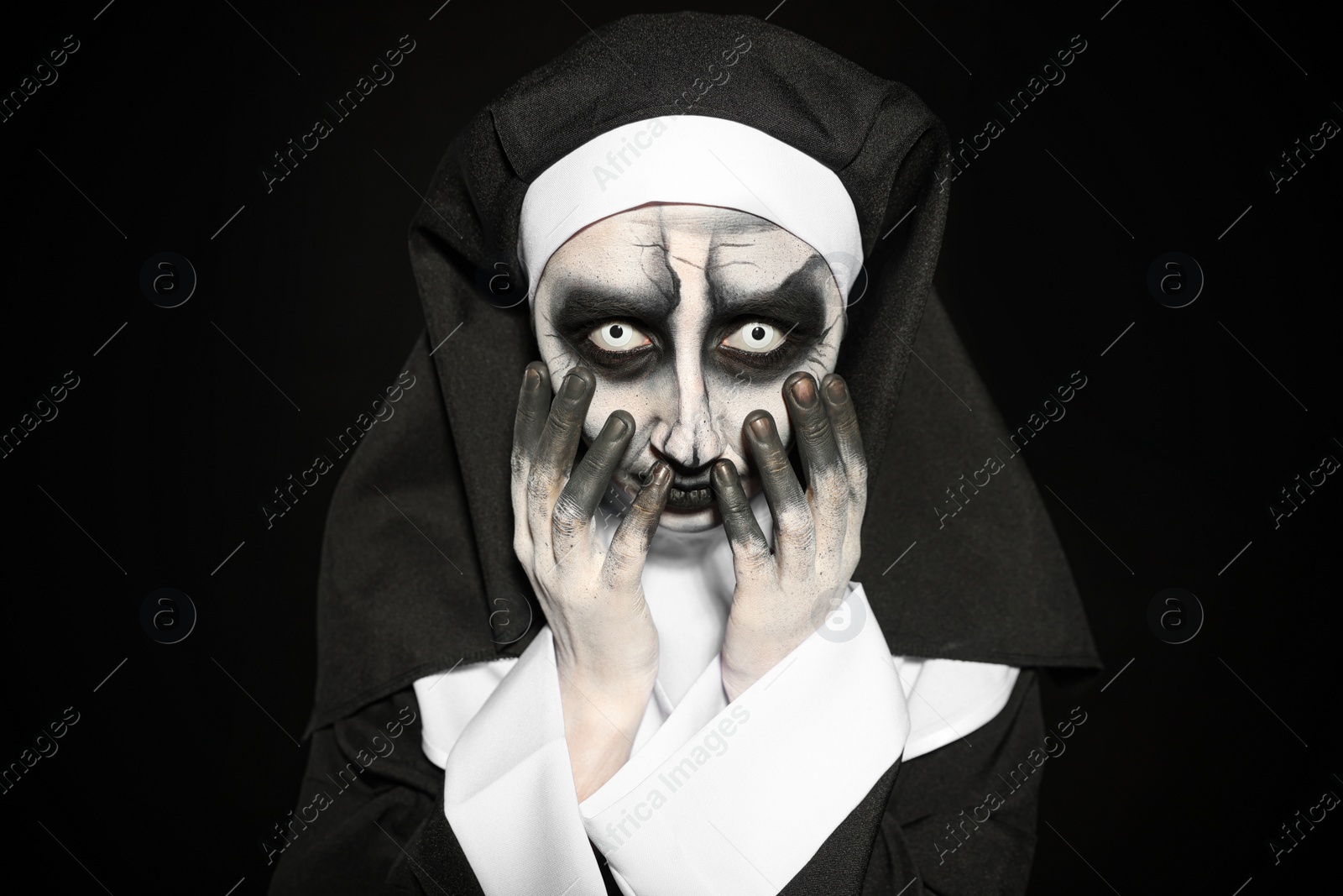 Photo of Portrait of scary devilish nun on black background. Halloween party look