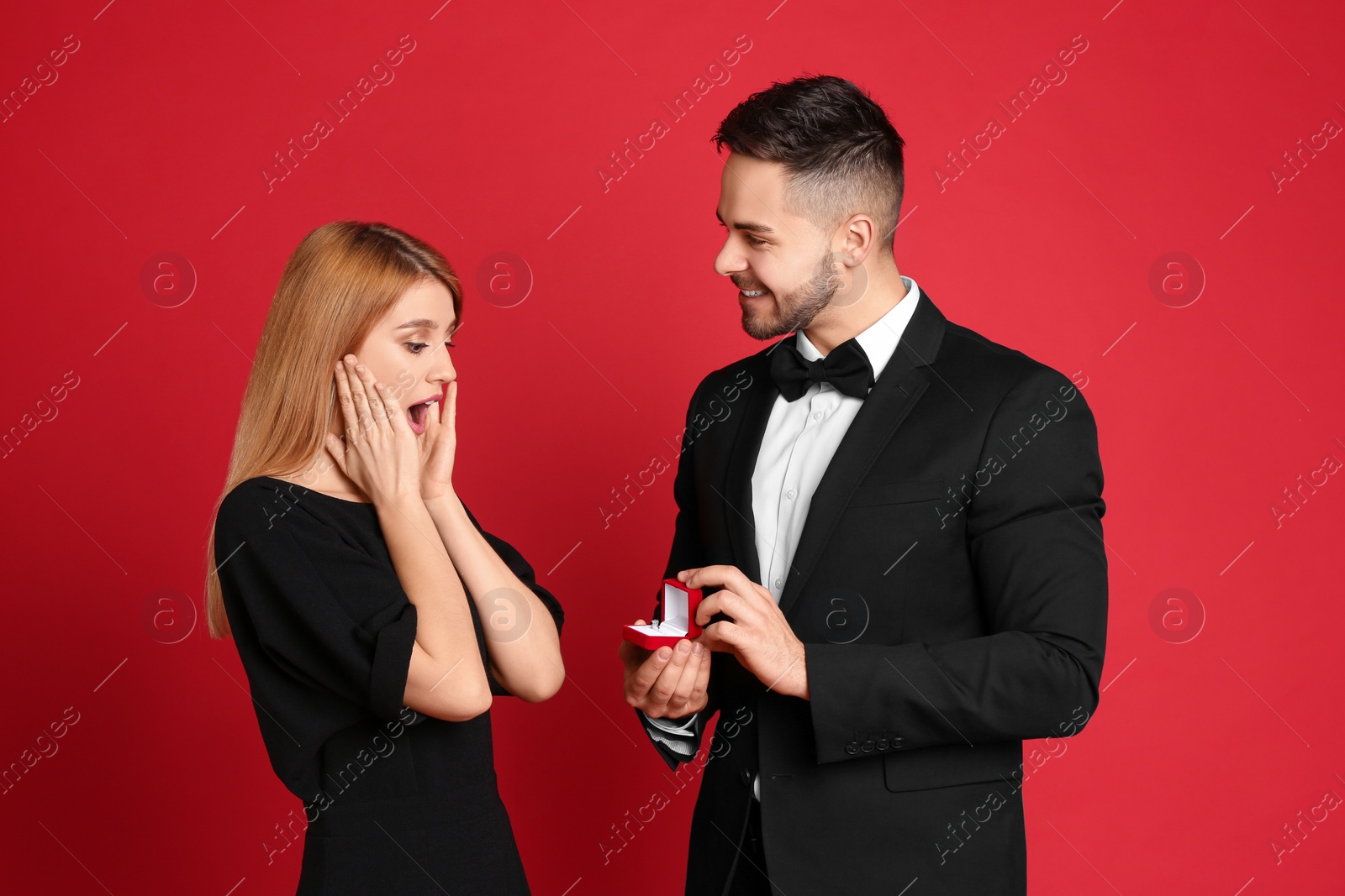 Photo of Man with engagement ring making marriage proposal to girlfriend on red background