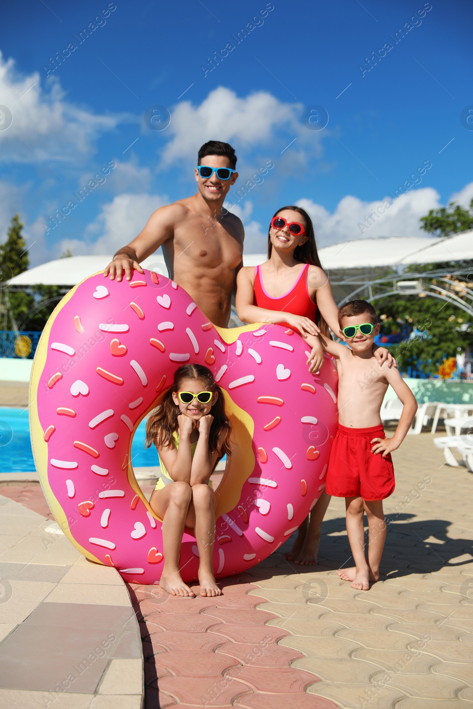 Photo of Happy family with inflatable ring near swimming pool.  Summer vacation
