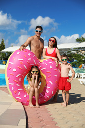 Happy family with inflatable ring near swimming pool.  Summer vacation