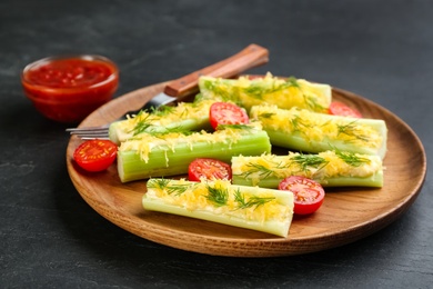 Celery sticks with sauce, cheese and tomatoes on black table, closeup