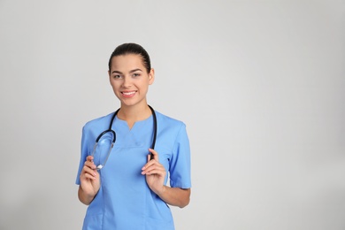 Portrait of young medical assistant with stethoscope on color background. Space for text