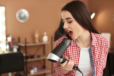 Photo of Funny hairdresser with blow dryer in beauty salon