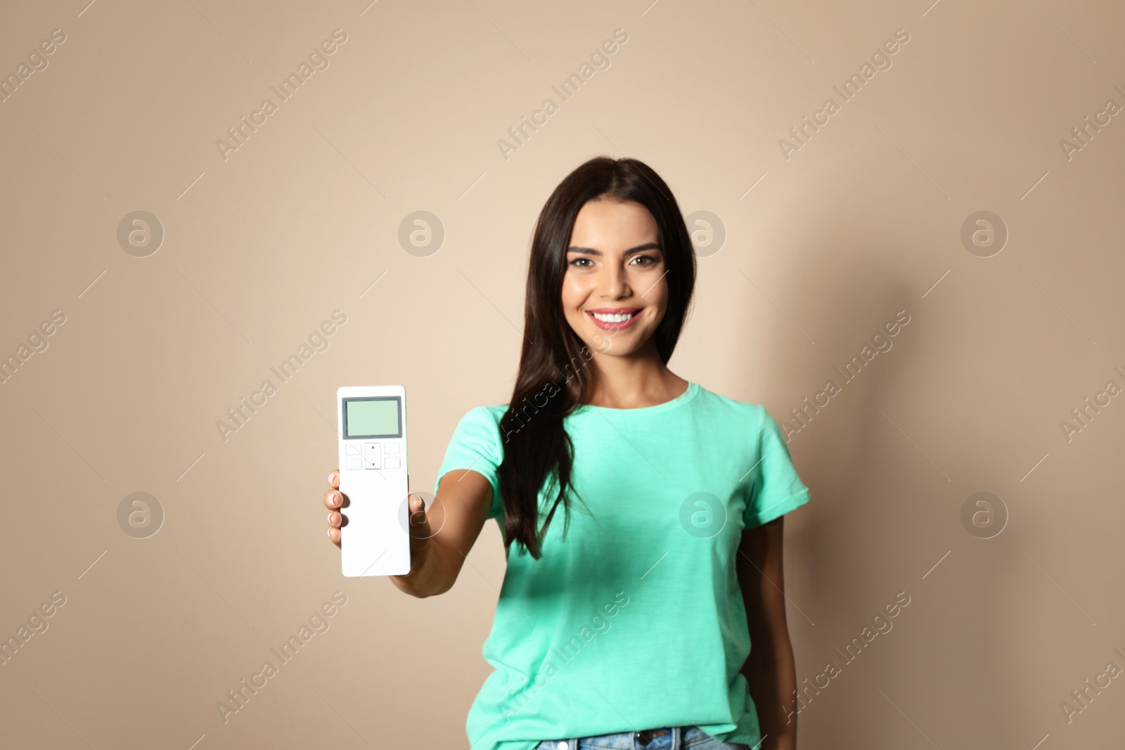 Photo of Young woman with air conditioner remote on beige background