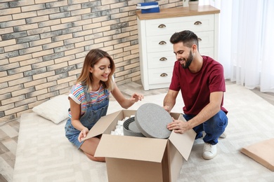 Photo of Young couple opening parcel on floor at home