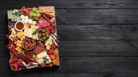 Assorted appetizers served on black wooden table, top view. Space for text