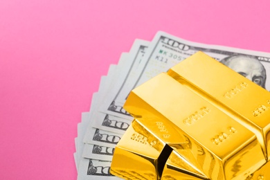 Photo of Shiny gold bars and dollar bills on color background