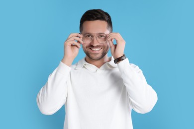 Portrait of happy man in stylish glasses on light blue background