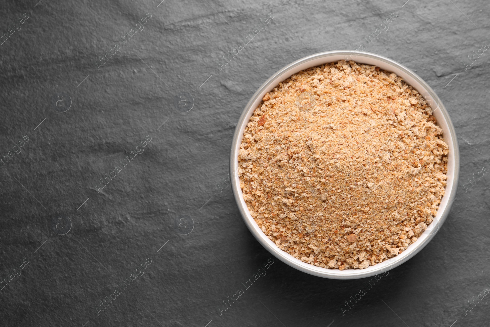 Photo of Fresh breadcrumbs in bowl on black table, top view. Space for text