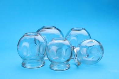 Photo of Glass cups on light blue background. Cupping therapy