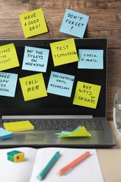 Photo of Many different reminder notes and laptop on table against wooden background