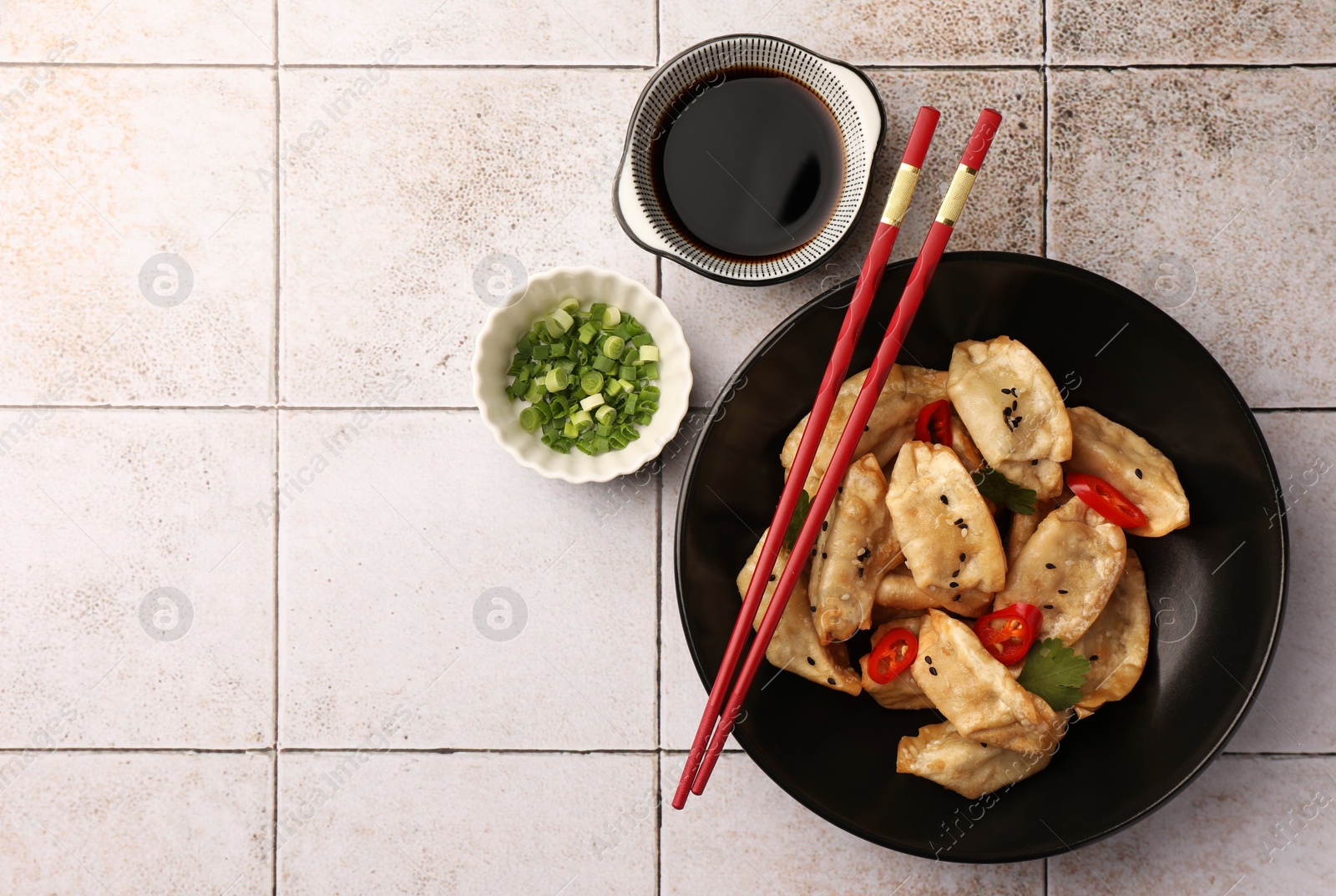 Photo of Delicious gyoza (asian dumplings) served on light tiled table, flat lay. Space for text