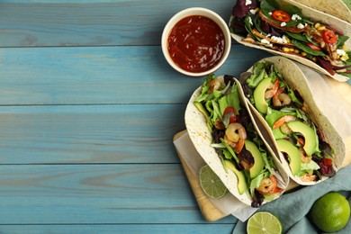 Photo of Delicious tacos with shrimps, avocado and lime on turquoise wooden table, flat lay. Space for text