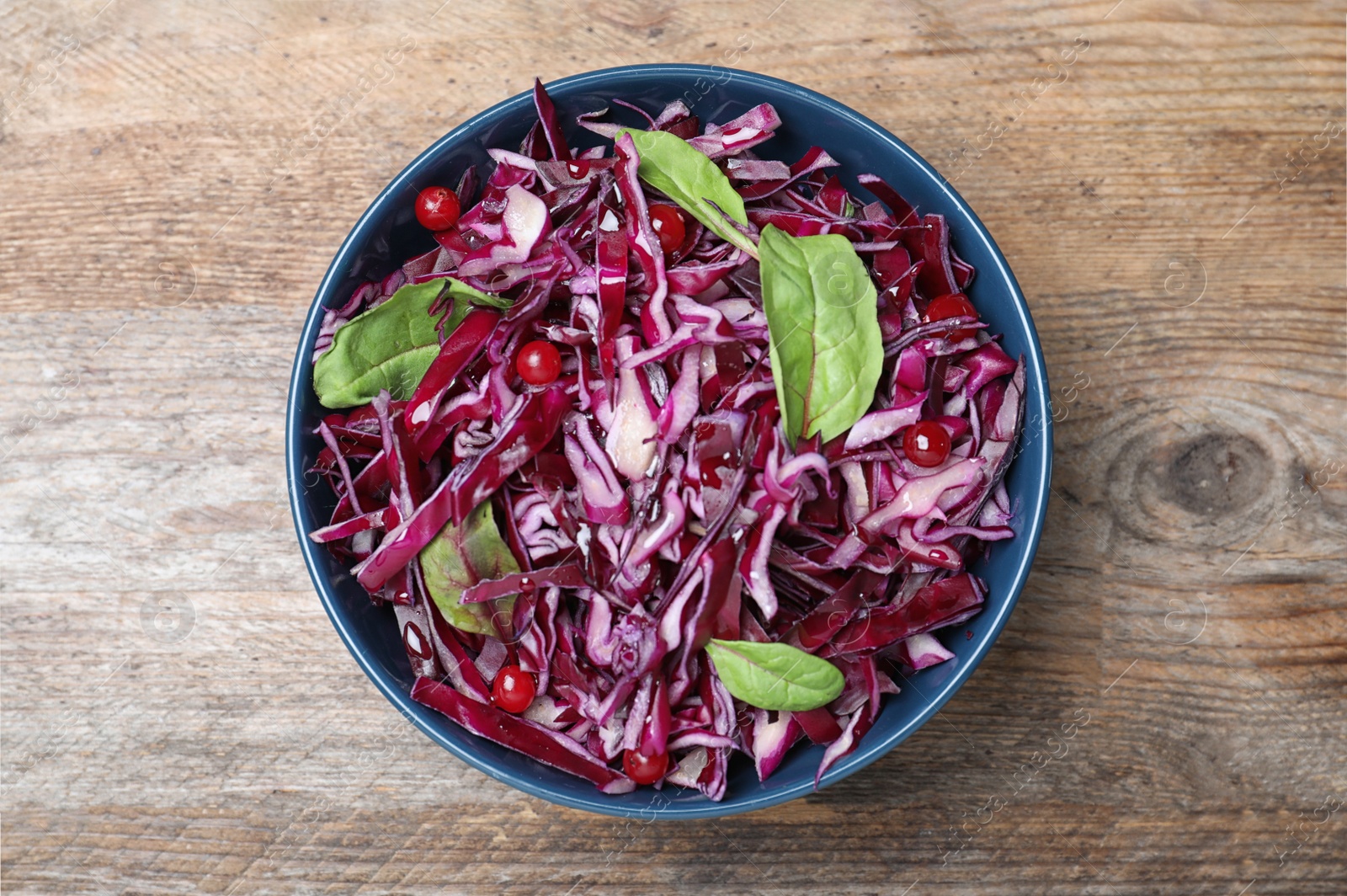 Photo of Fresh red cabbage salad served on wooden table, top view