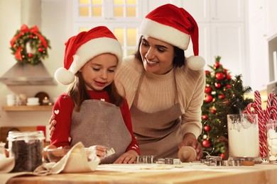 Photo of Happy mother and her daughter making delicious Christmas cookies at home