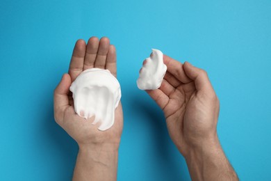 Photo of Man holding shaving foam on light blue background, top view