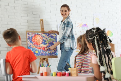 Children with female teacher at painting lesson indoors