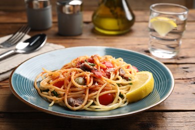 Photo of Delicious pasta with anchovies, tomatoes and parmesan cheese served on wooden table, closeup