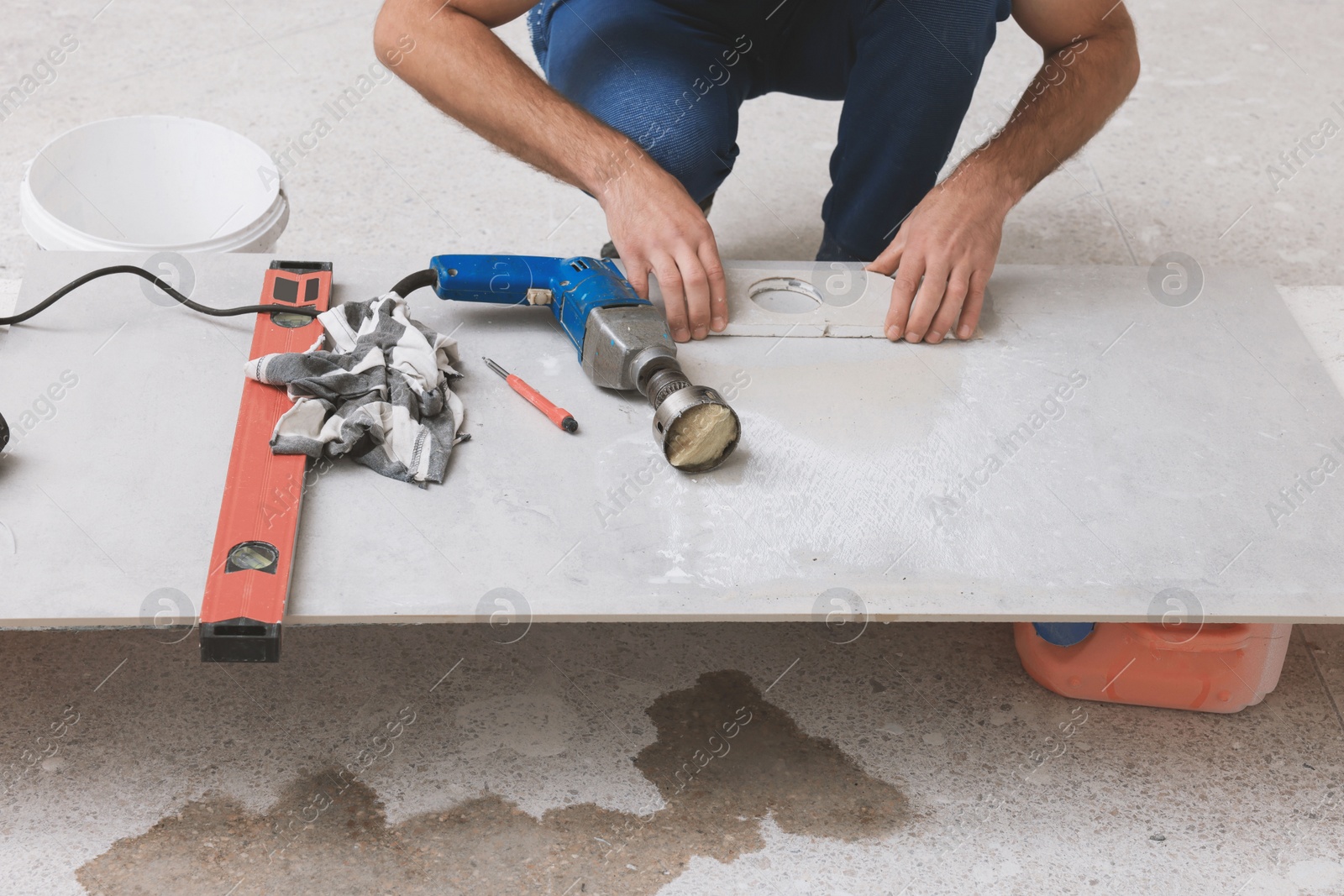 Photo of Worker making socket hole in tile indoors, closeup