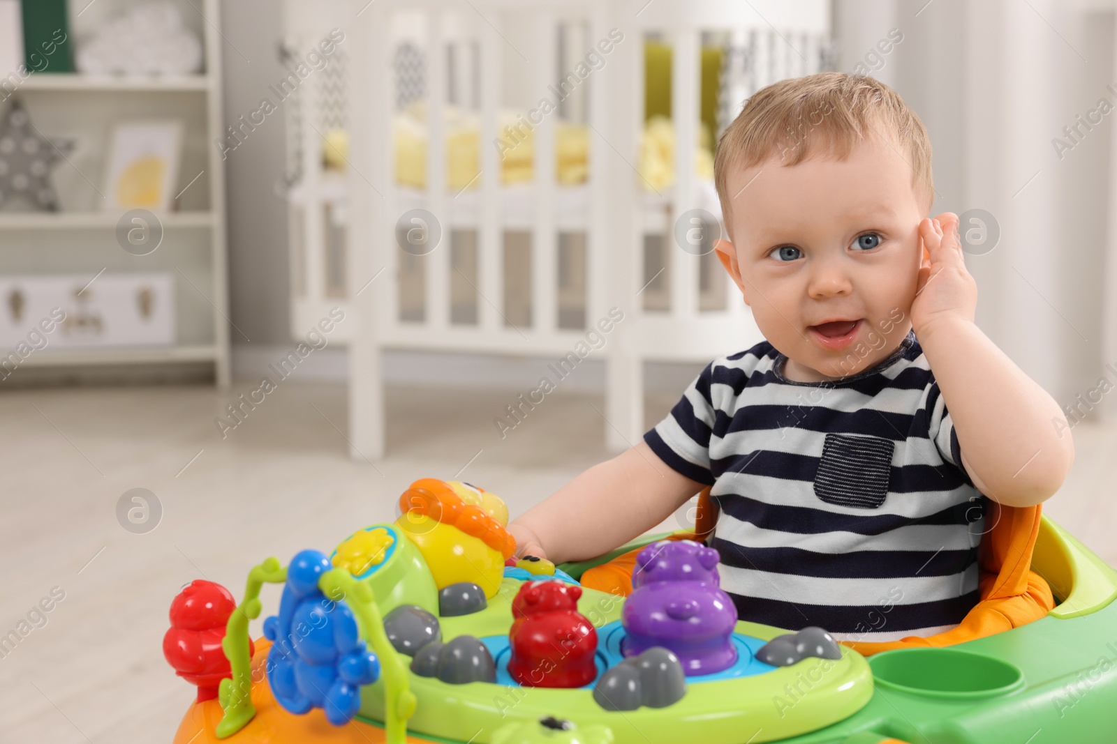 Photo of Portrait of cute baby with toy walker at home, space for text. Learning to walk