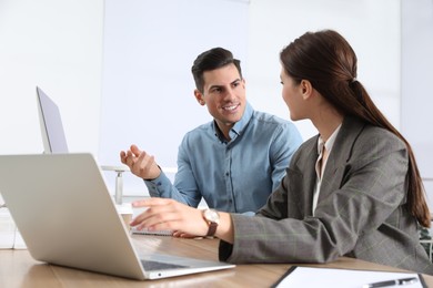 Businesswoman helping intern with work in office