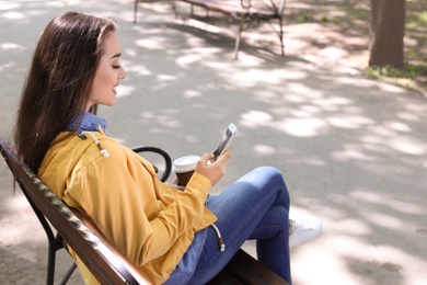 Young woman using phone outdoors on sunny day