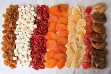Photo of Different tasty dried fruits on paper, flat lay