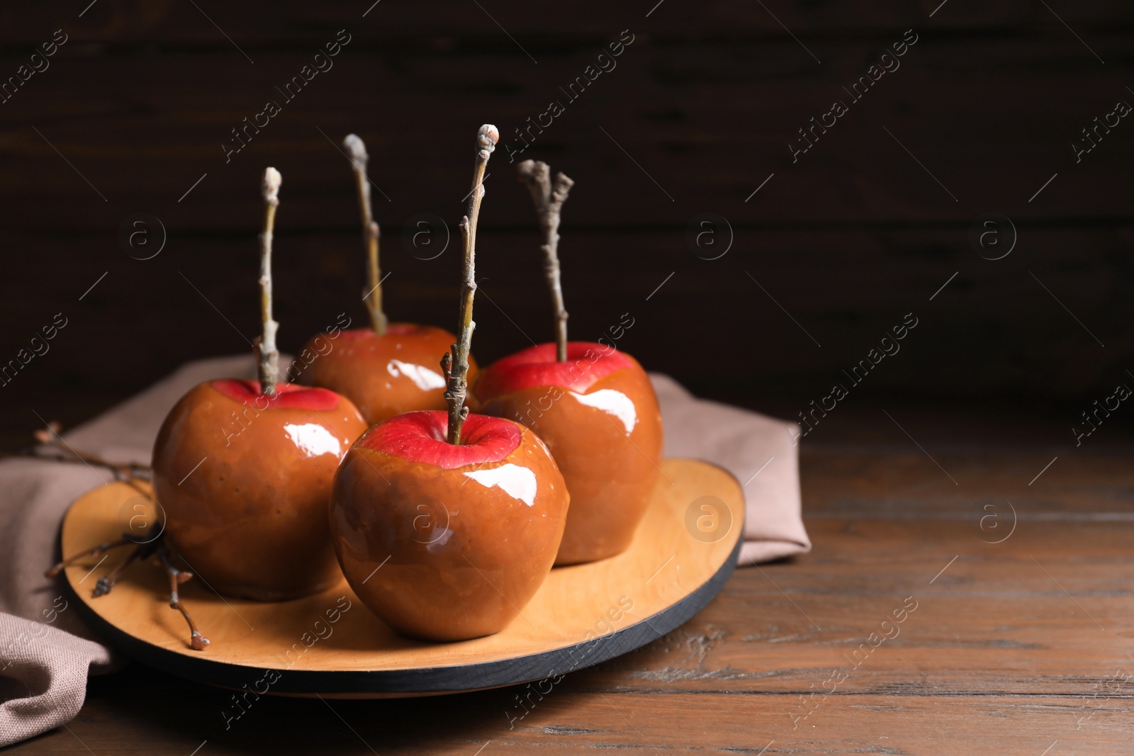 Photo of Plate with delicious caramel apples on wooden table