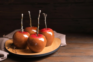 Photo of Plate with delicious caramel apples on wooden table