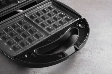 Photo of Modern waffle iron on grey stone table, closeup