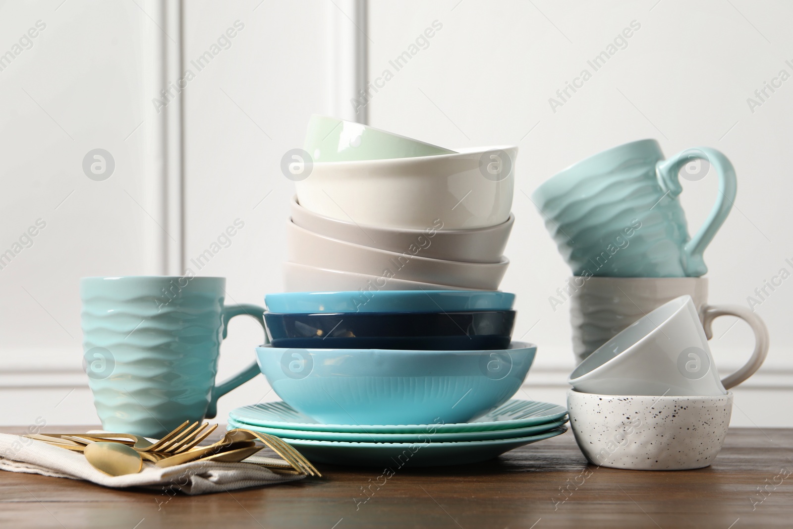 Photo of Beautiful ceramic dishware, cups and cutlery on wooden table