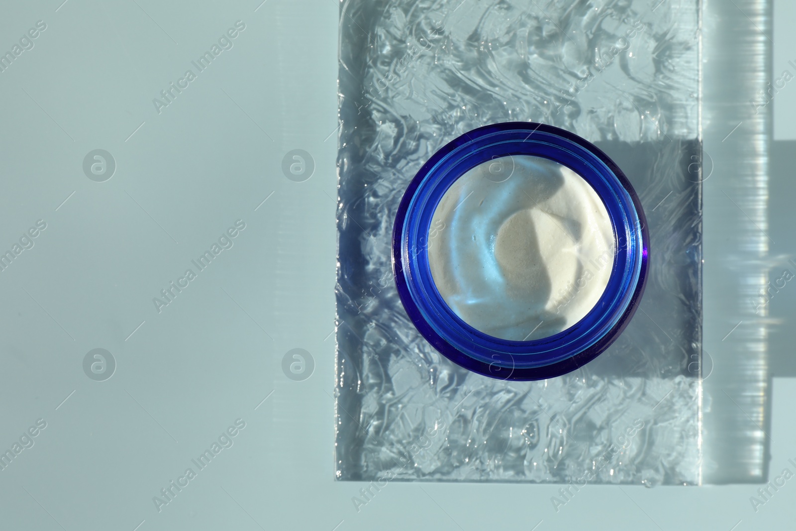 Photo of Jar of moisturizing cream on light blue background, top view. Space for text
