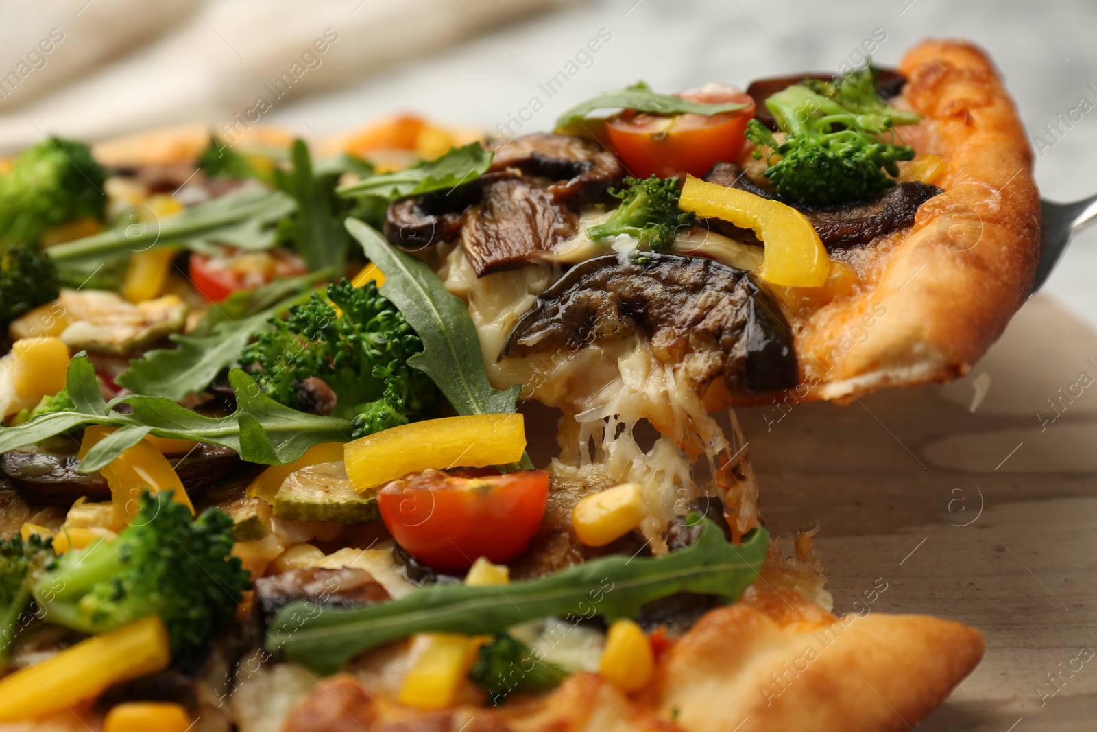 Photo of Taking piece of delicious vegetarian pizza at table, closeup