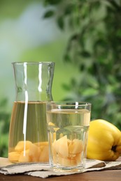 Photo of Delicious quince drink and fresh fruits on wooden table against blurred background