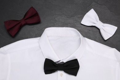Photo of Stylish color bow ties and white shirt on grey background, flat lay