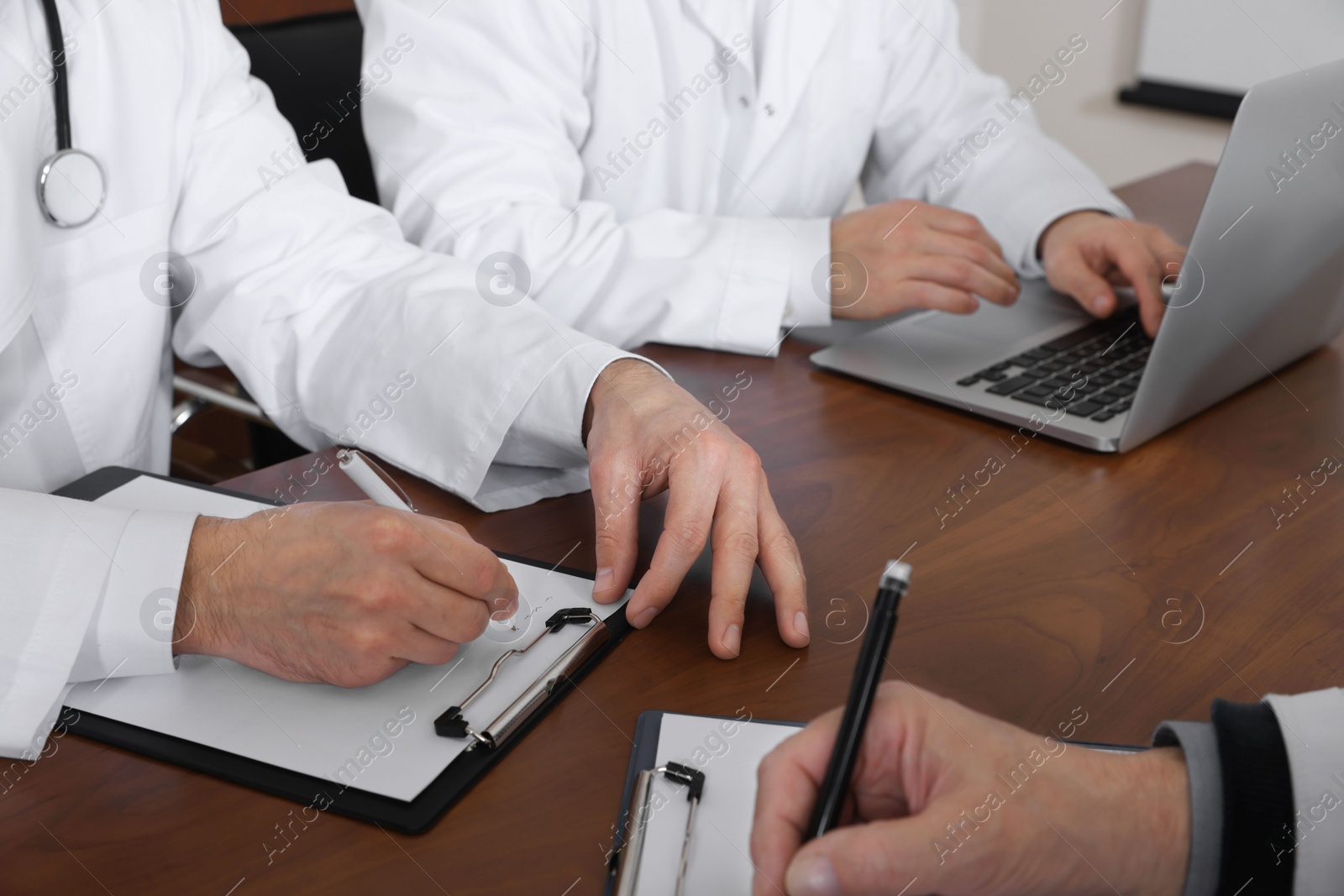 Photo of Team of doctors working with papers during medical conference indoors, closeup