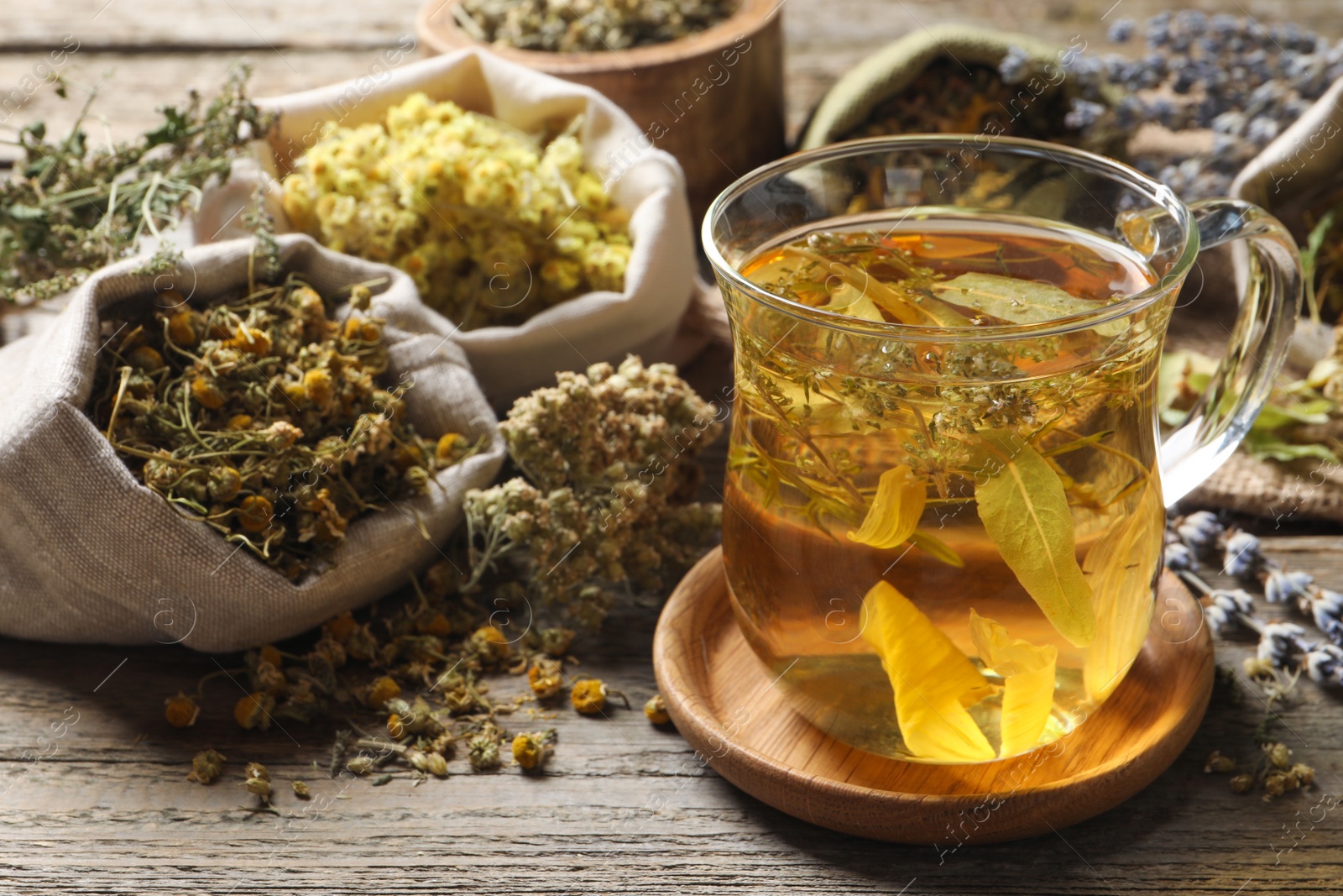 Photo of Freshly brewed tea and dried herbs on wooden table