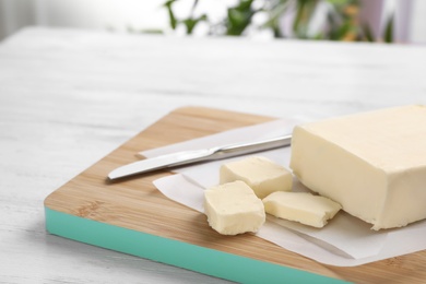 Photo of Wooden board with tasty fresh butter on table