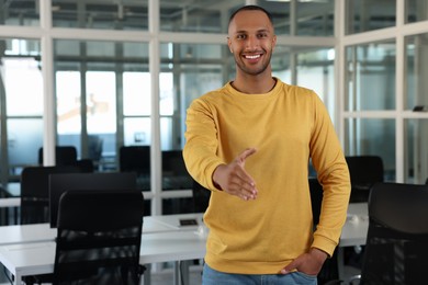 Photo of Happy man welcoming and offering handshake in office, space for text
