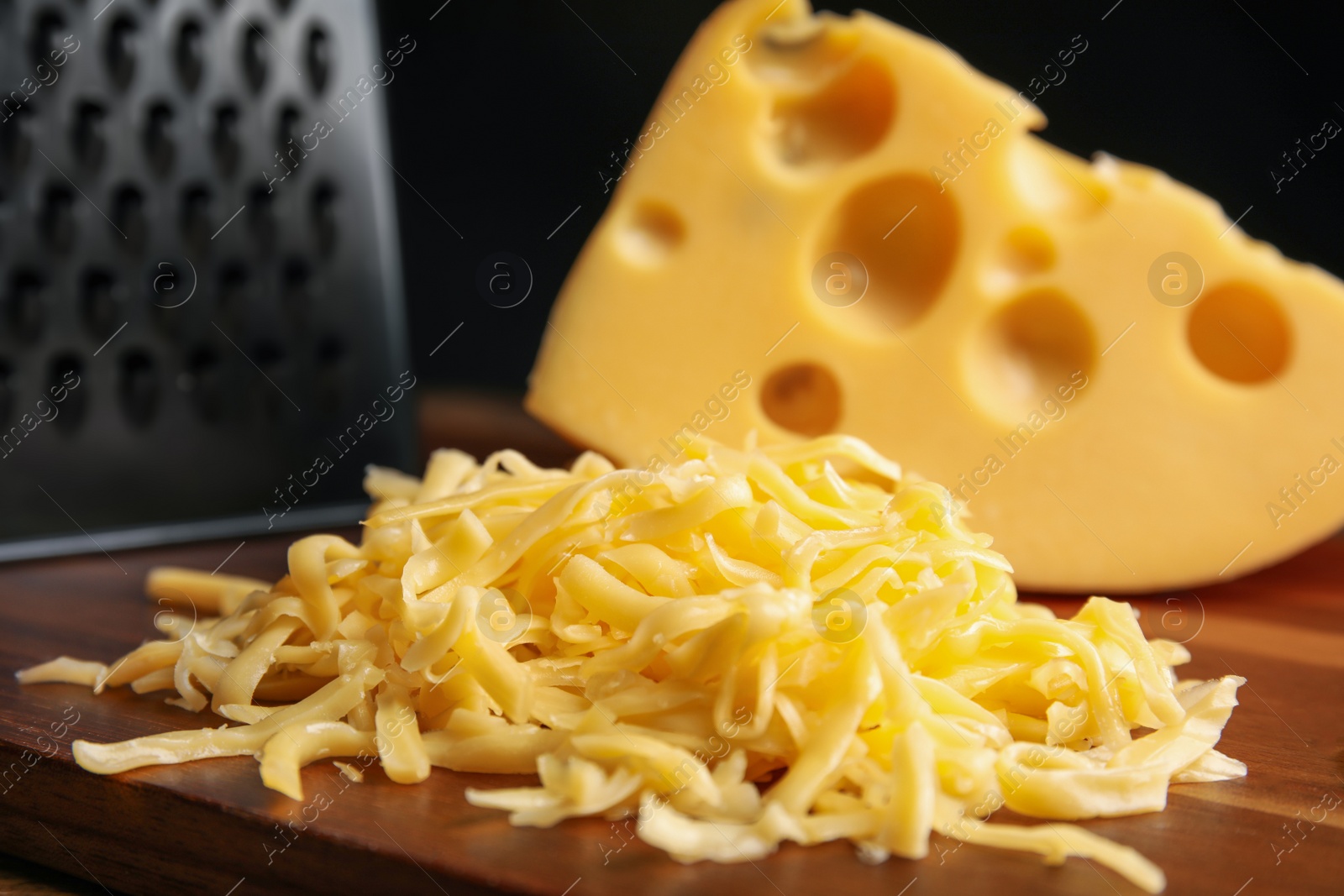 Photo of Tasty grated cheese on wooden table, closeup