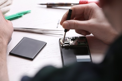 Photo of Technician fixing mobile phone at table, closeup. Device repair service