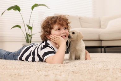 Photo of Little boy with cute puppy on beige carpet indoors