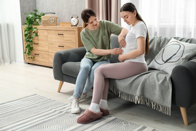 Doula taking care of pregnant woman on sofa at home. Preparation for child birth