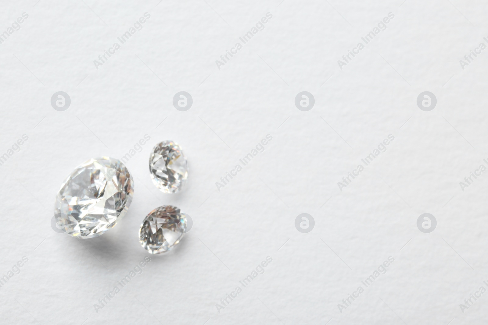 Photo of Beautiful shiny diamonds on white background, flat lay. Space for text