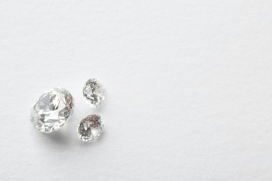Beautiful shiny diamonds on white background, flat lay. Space for text