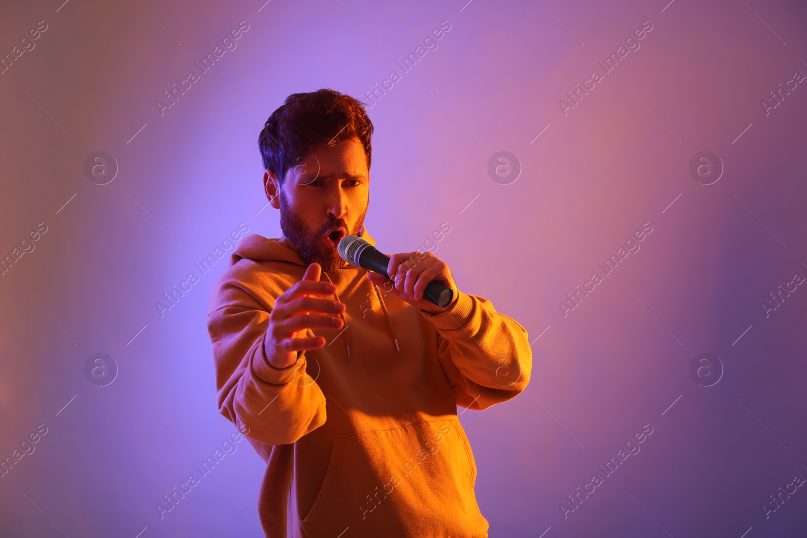 Photo of Singer with microphone rapping in color lights