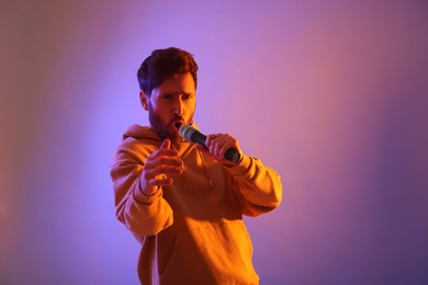 Photo of Singer with microphone rapping in color lights