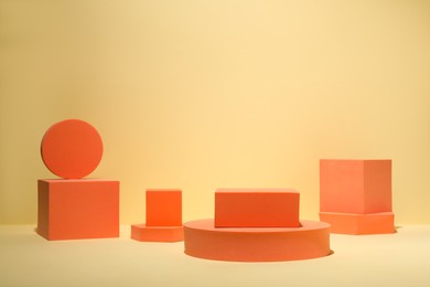 Photo of Many orange geometric figures on table against yellow background, space for text. Stylish presentation for product
